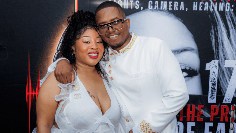 A couple poses together, smiling, at a formal event with a red carpet backdrop