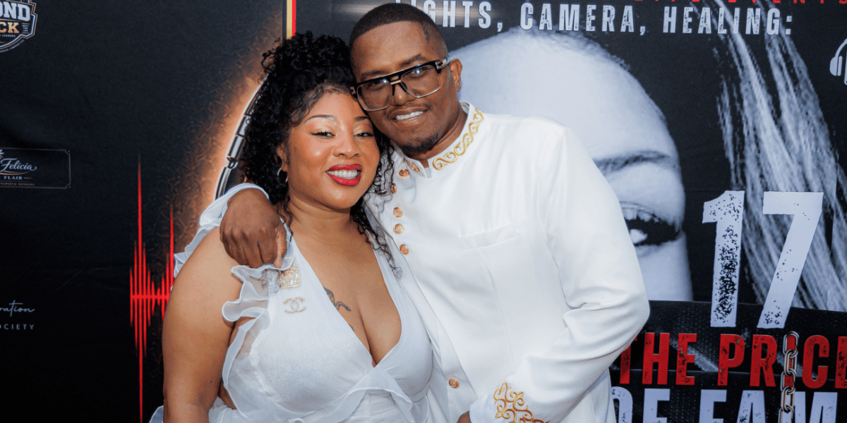 A couple poses together, smiling, at a formal event with a red carpet backdrop