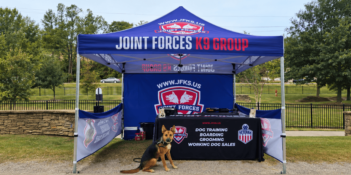 A promotional tent for Joint Forces K9 Group with a dog sitting in front