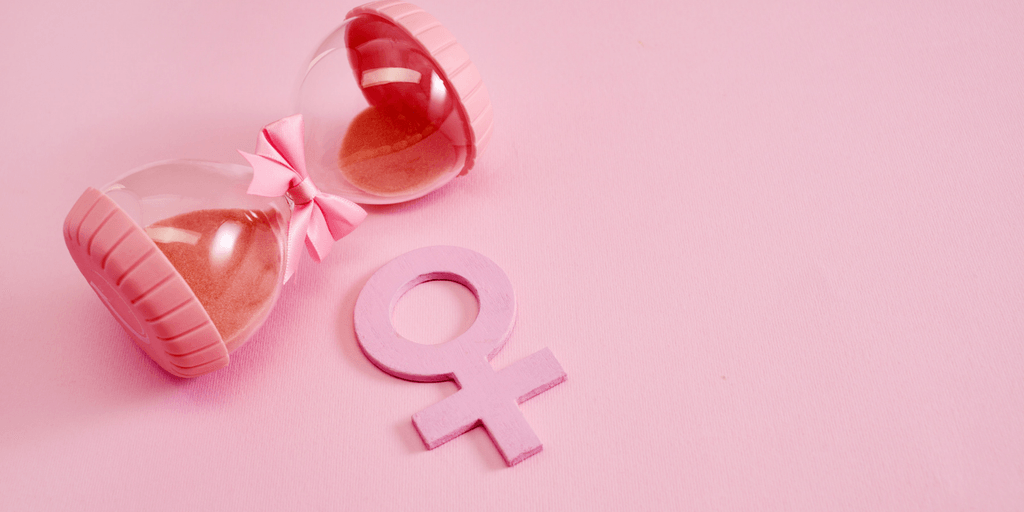 Pink hourglass with a bow next to a pink female gender symbol