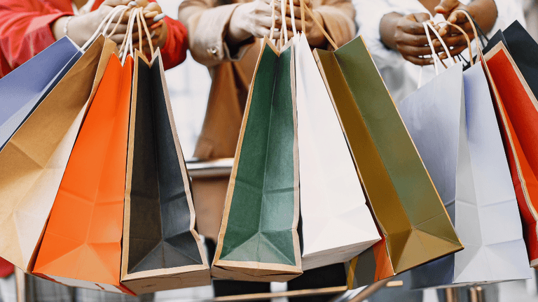 Group of people holding colorful shopping bags in a semi-urban setting