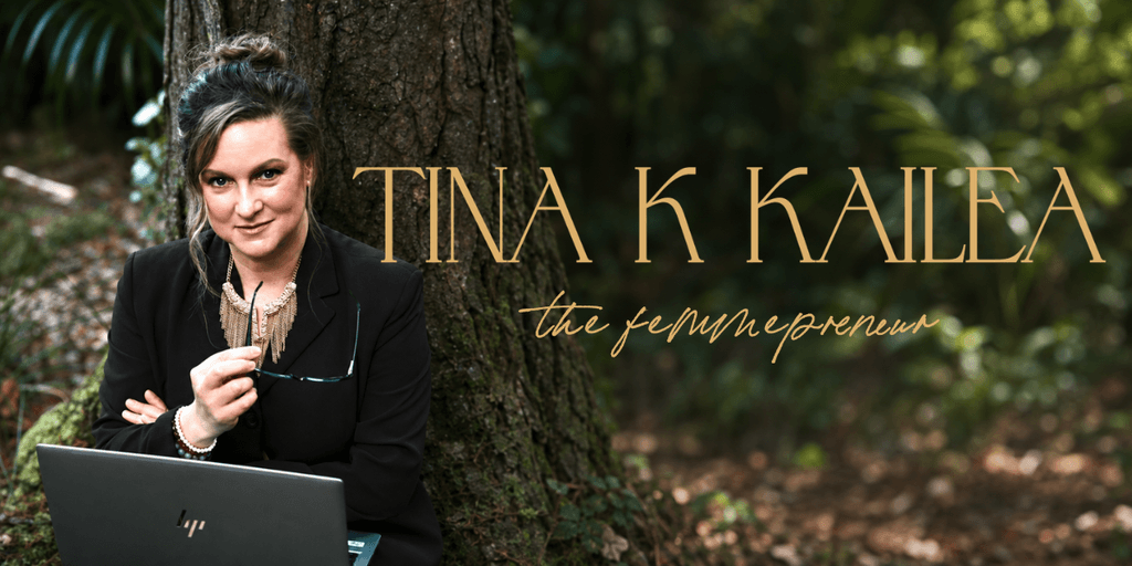 A woman in business attire sitting outdoors, holding glasses near a laptop.