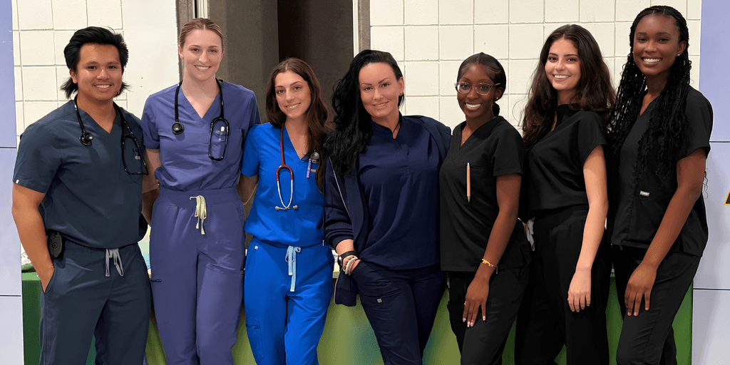 Group of seven healthcare professionals posing together in scrubs and medical attire