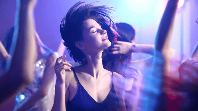 A woman dancing joyfully in a vibrant, colorful party atmosphere with swirling lights