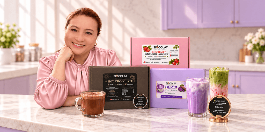Woman smiling behind various colorful beverage products on a kitchen counter.