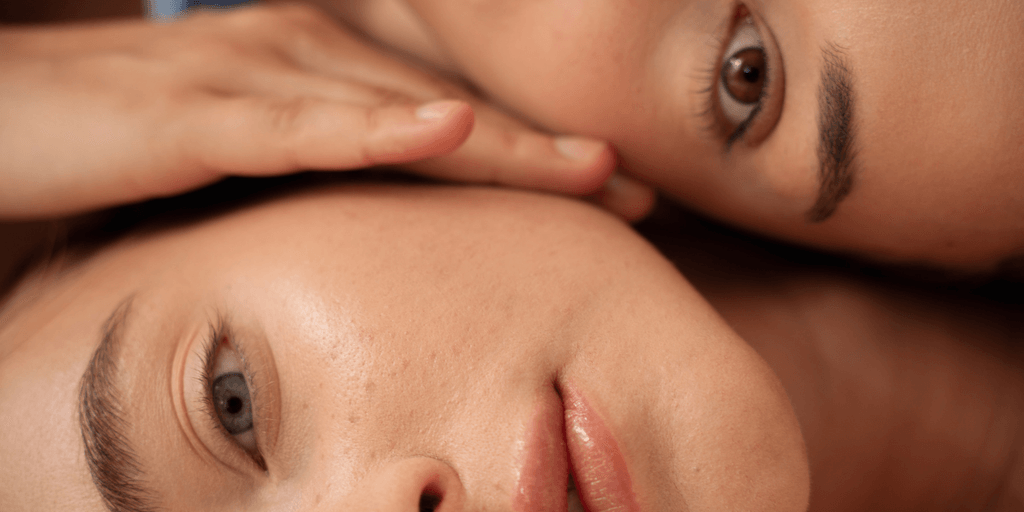 Two close-up faces with soft features and expressive eyes, resting against each other