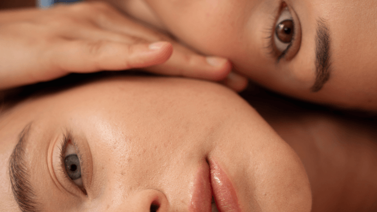 Two close-up faces with soft features and expressive eyes, resting against each other