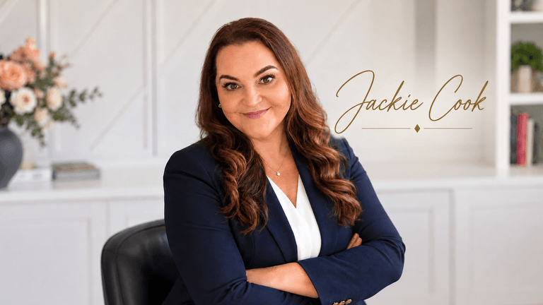 Professional woman in a blazer sitting with arms crossed, smiling at the camera