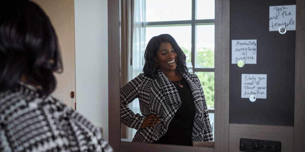 Woman smiling while posing in front of a mirror in a stylish room
