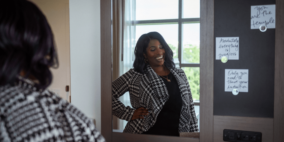 Woman smiling while posing in front of a mirror in a stylish room