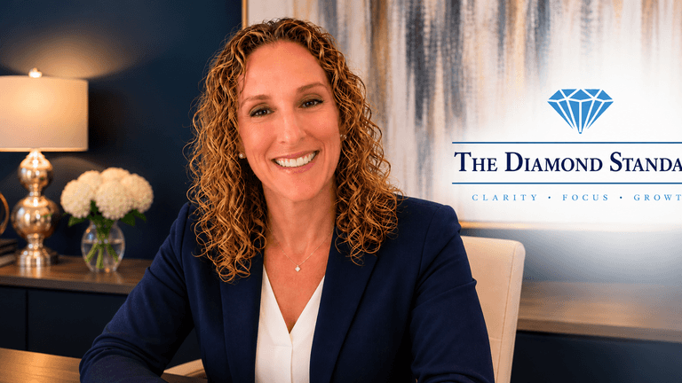A smiling woman in a suit sitting at a desk with a logo for The Diamond Standard