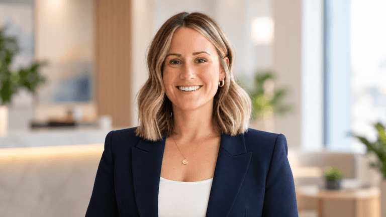 Smiling woman in a navy blazer standing in a modern office space