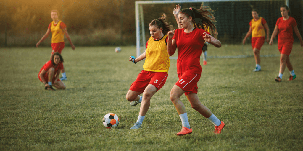 Two female soccer players compete for the ball on a grassy field