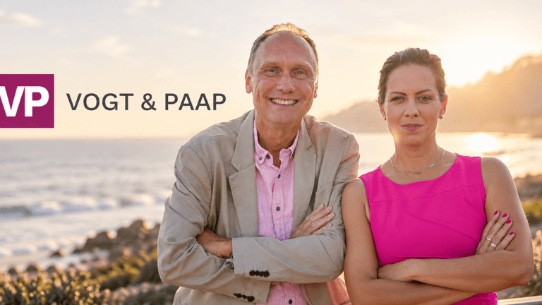 Two professionals standing by the beach at sunset with a logo on the left