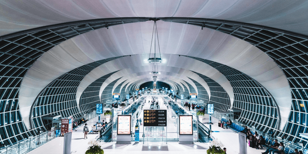 Modern airport interior showcasing curved architecture and busy passenger flow throughout terminal
