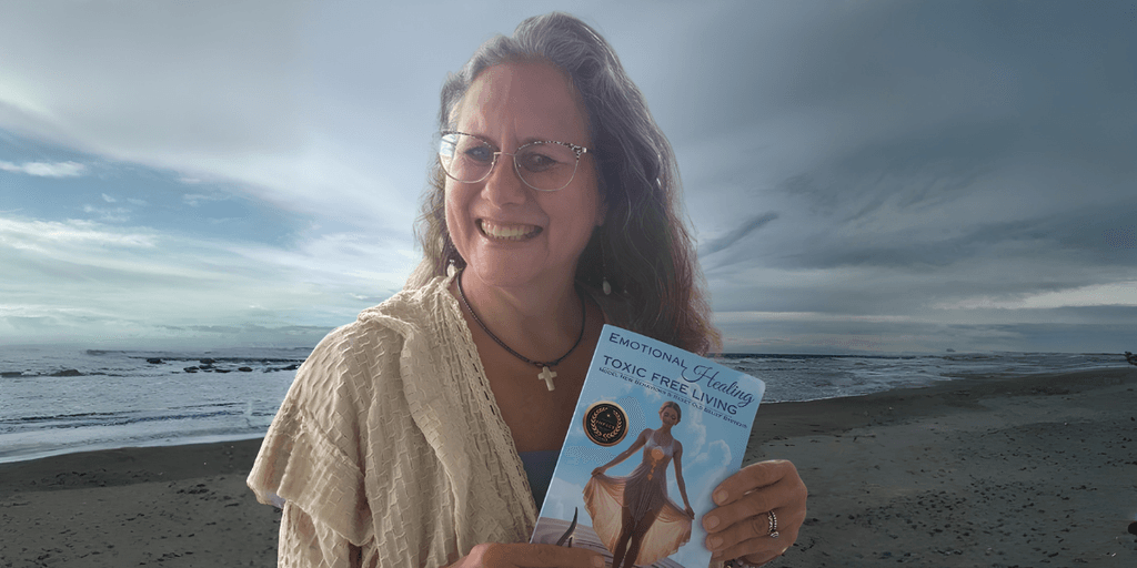Woman smiling while holding a book by the beach under a cloudy sky