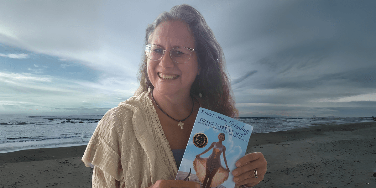 Woman smiling while holding a book by the beach under a cloudy sky