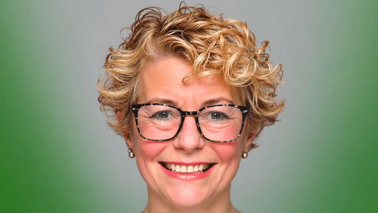 Smiling woman with short curly hair and glasses against a gradient green background