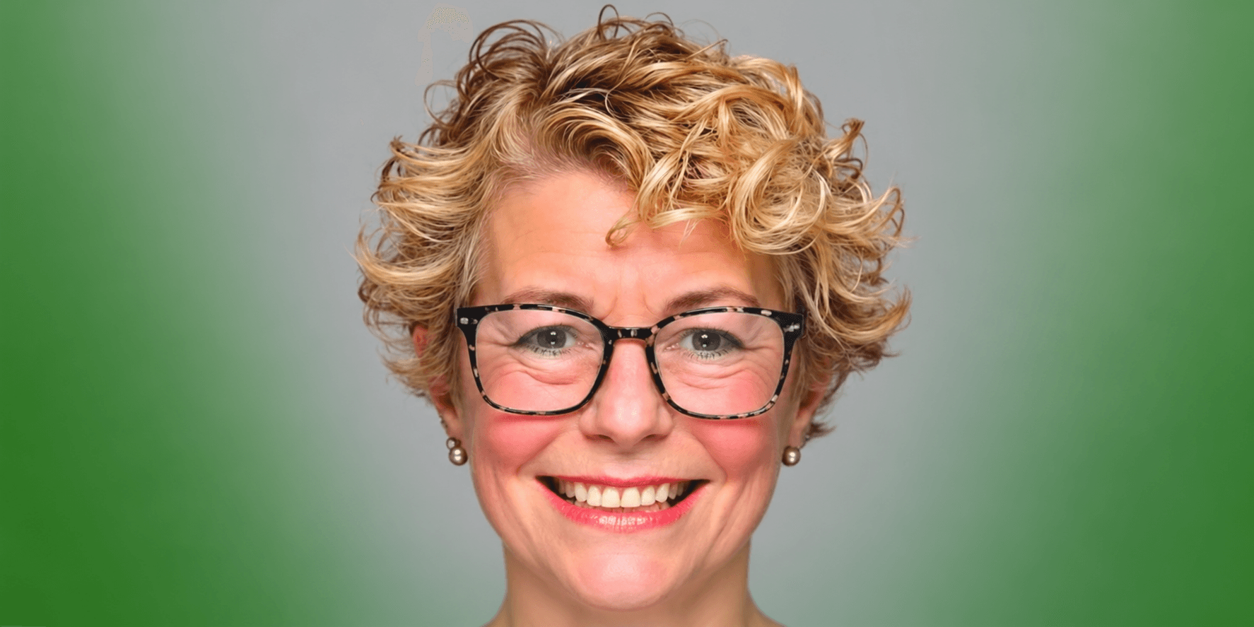 Smiling woman with short curly hair and glasses against a gradient green background