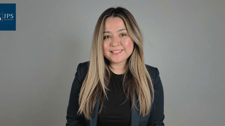 Smiling woman with long hair in a blazer against a light gray background