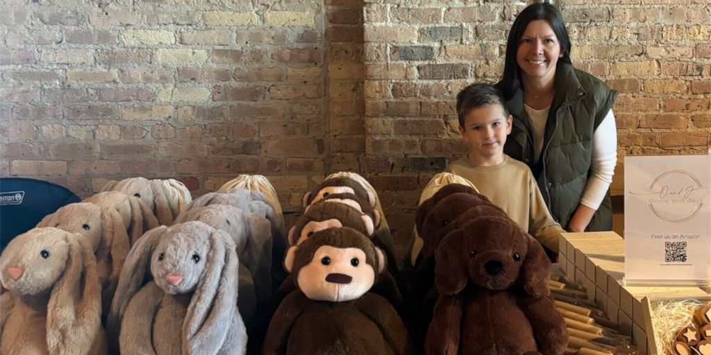 A mom and her child stand behind a display of plush sensory toys, including bunnies, monkeys, and dogs.