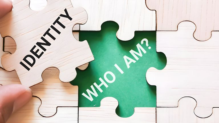 A hand places a puzzle piece labeled "IDENTITY" into a missing space with the words "WHO I AM?" in green.