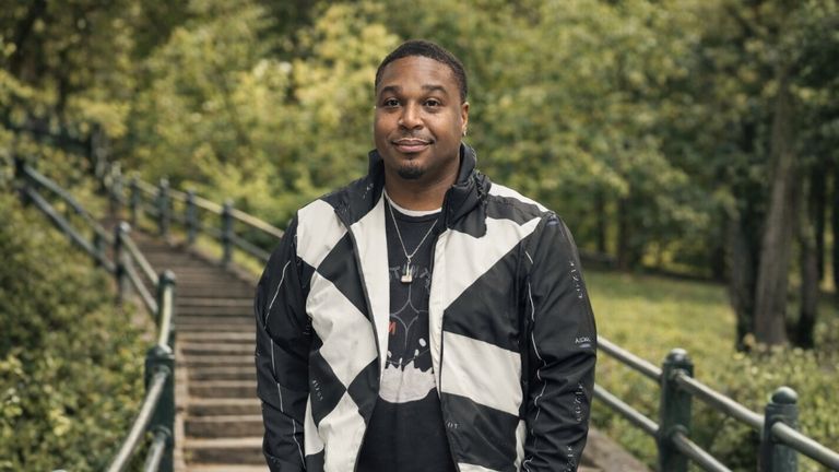 A confident man in streetwear jacket stands in front of outdoor stairs, embodying Toxik Nature's bold, expressive style.