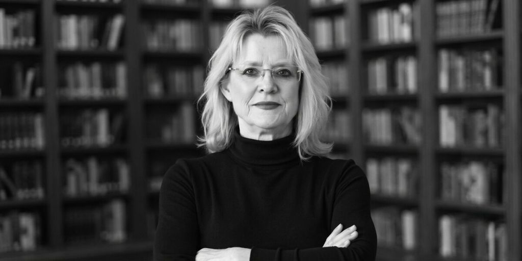 Sandra K. Griffith in front of bookshelves with arms crossed.