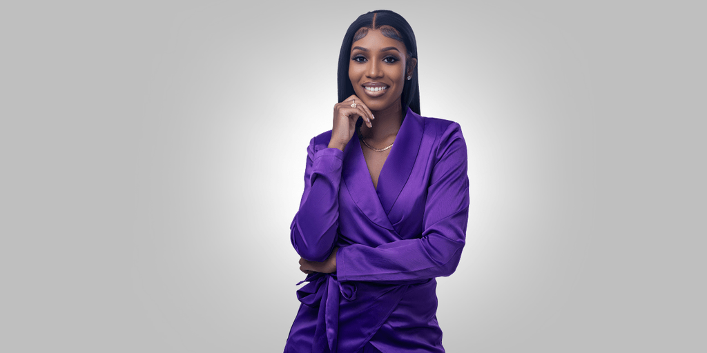 Ashmara Lawrence, a financial coach, smiles confidently in a purple blouse, empowering women to build generational wealth.