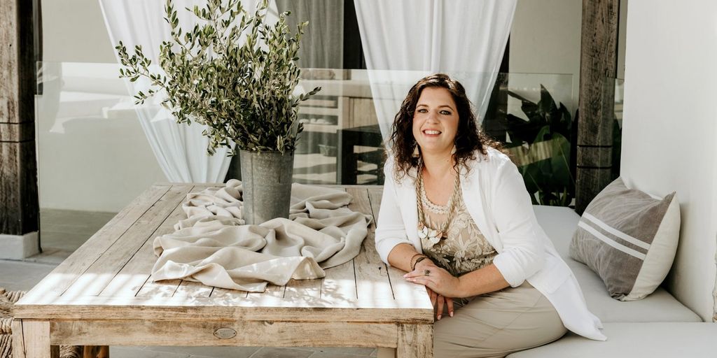 Vanessa Grace sitting at a table with a relaxed, welcoming smile, surrounded by natural decor.