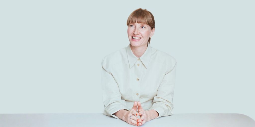 Helene Christensen, founder of Eksakt, smiling and seated, embodying calm and clarity as she discusses personal transformation.