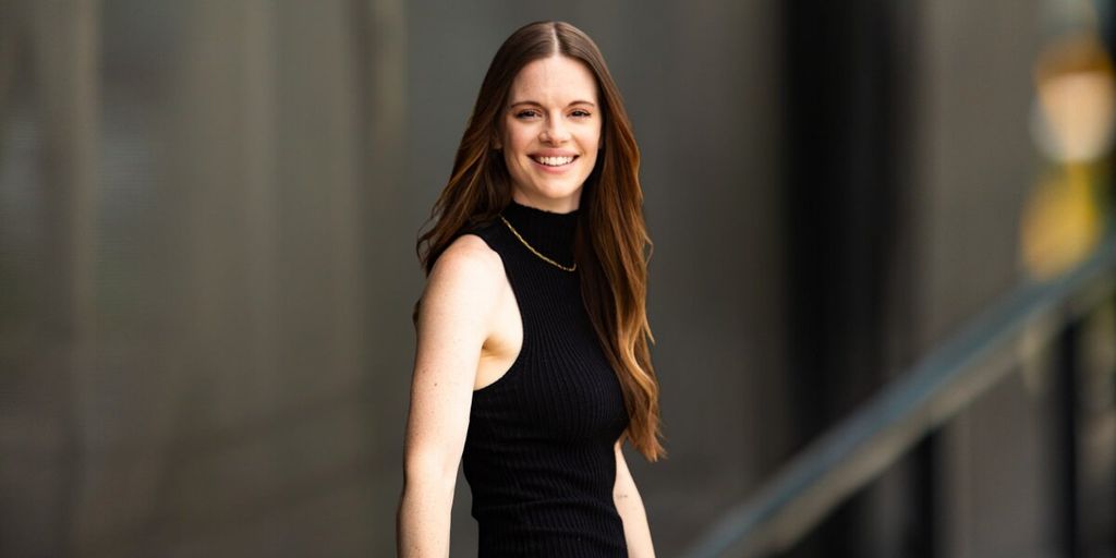 Elle Army is smiling, standing confidently outdoors in a black sleeveless turtleneck, showcasing a compassionate, professional demeanor.