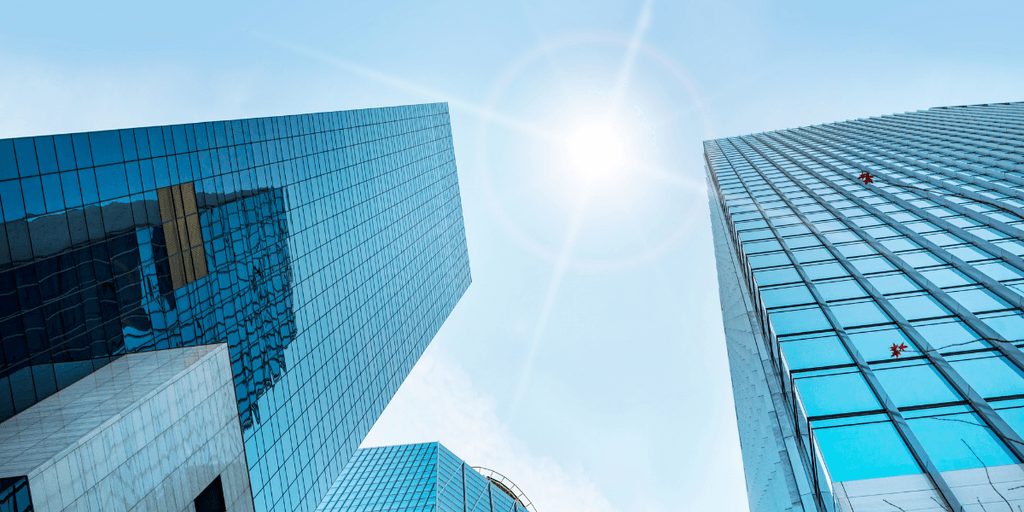 Modern glass office towers beneath a bright blue sky, representing business innovation and corporate growth.