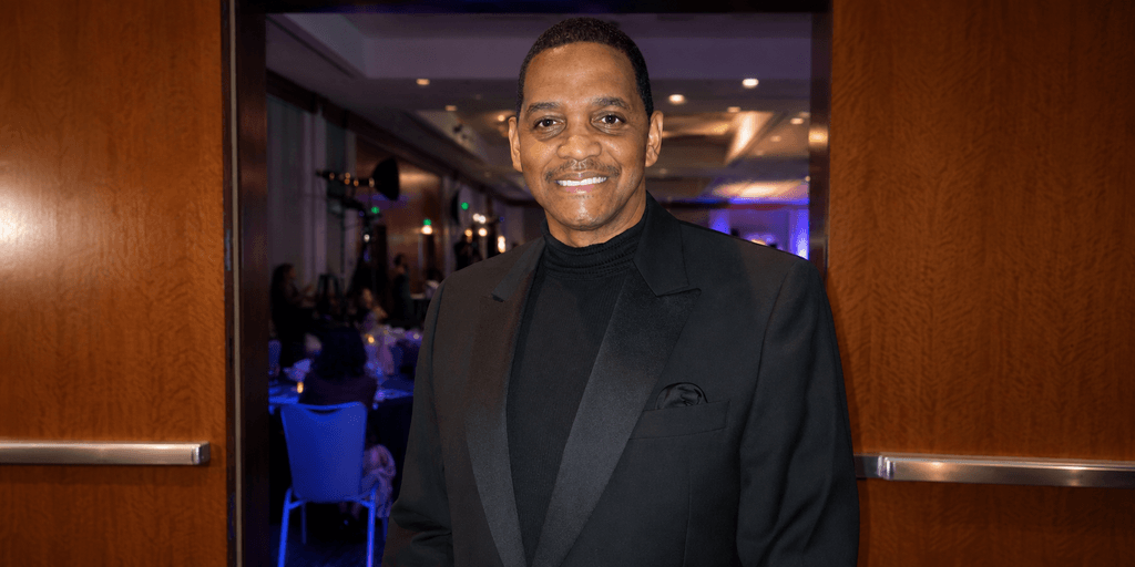 Prof. Robert Stewart smiles at a formal evening event in a black tuxedo and turtleneck.”