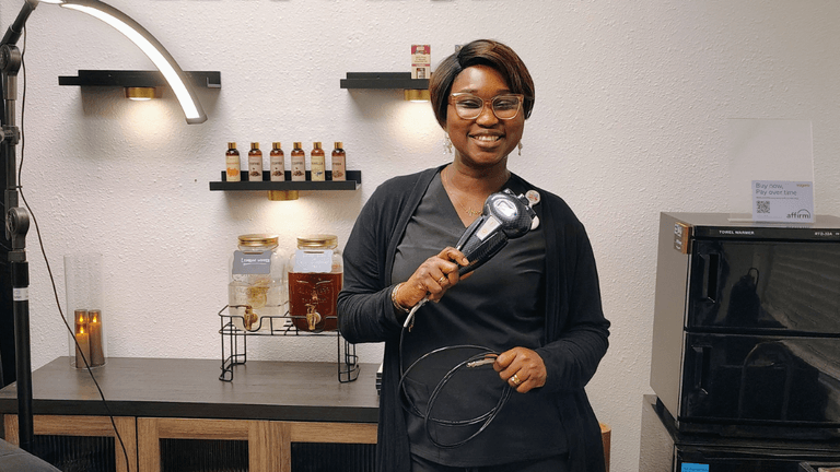 Nurse Olu holding a body contouring device inside the CryoEmpress Wellness studio.