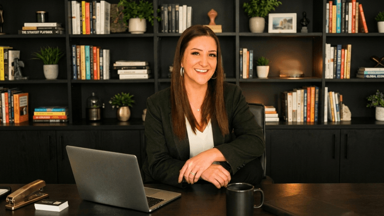 Hilary Russell seated at a desk with a laptop in front of bookshelves in an office.