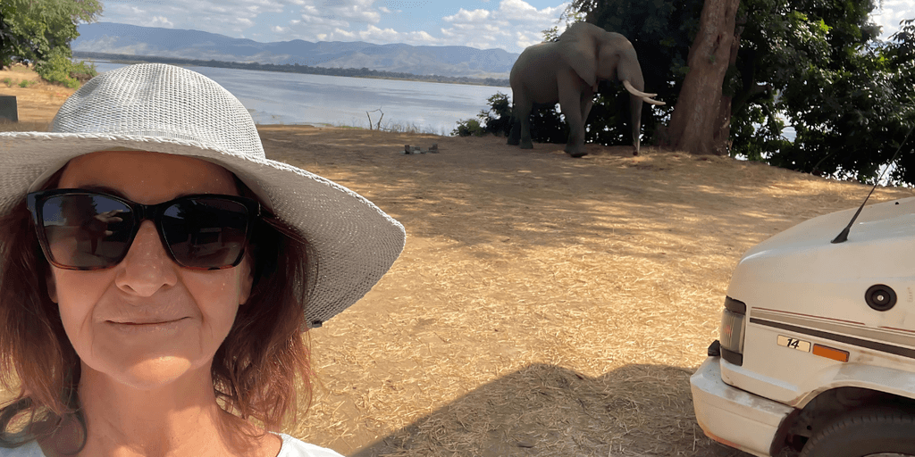 A woman enjoys a scenic moment with an elephant while reflecting on gender and storytelling.