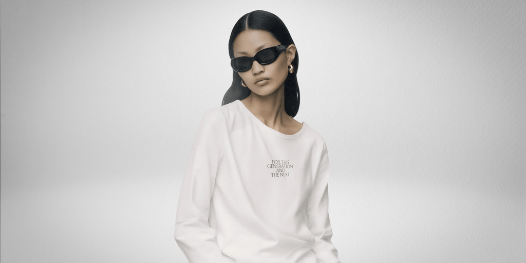 Model wearing FCCW’s AI-designed white sweatshirt with sunglasses; text on shirt reads “For This Generation and the Next.”