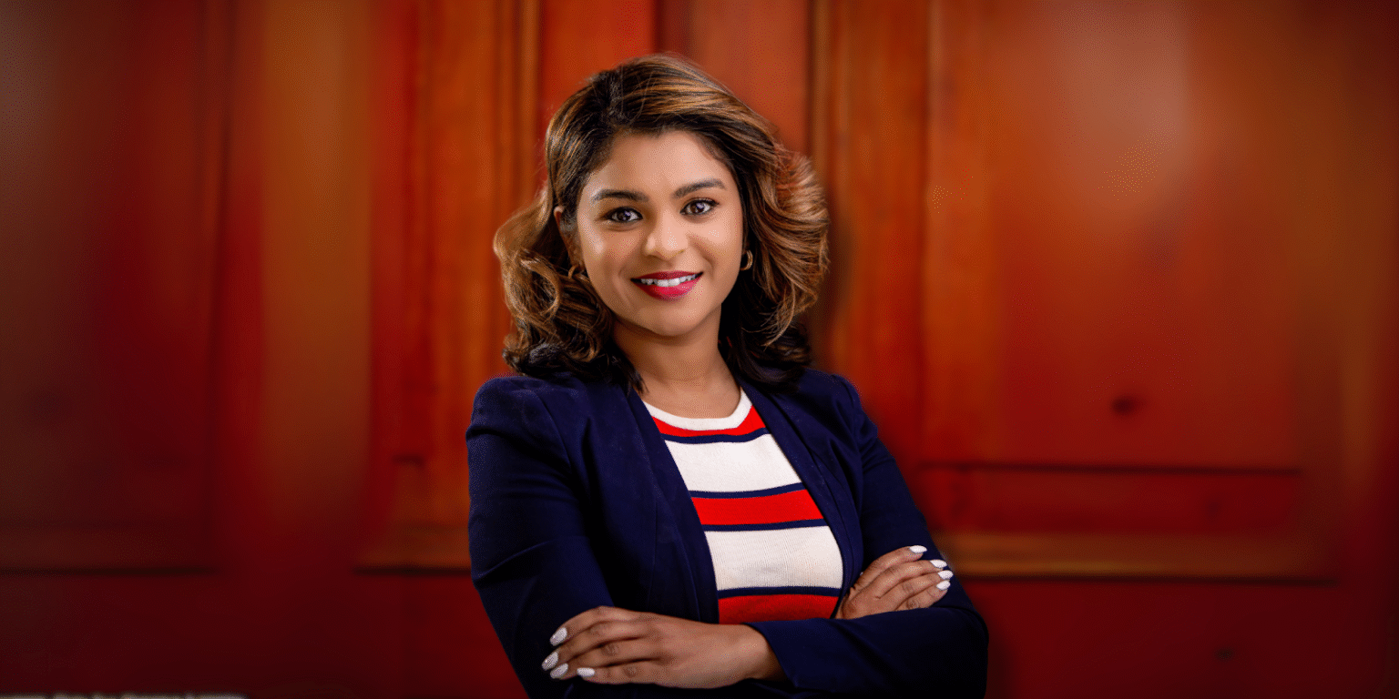 Professional headshot of a woman with a stylish bob haircut, dressed in a striped red, white, and blue top paired with a navy blue blazer, with a warm and approachable expression.