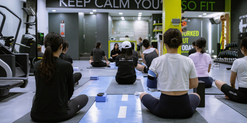 Group of people practicing yoga in a modern fitness studio, focusing on meditation and mindfulness with a calming atmosphere.