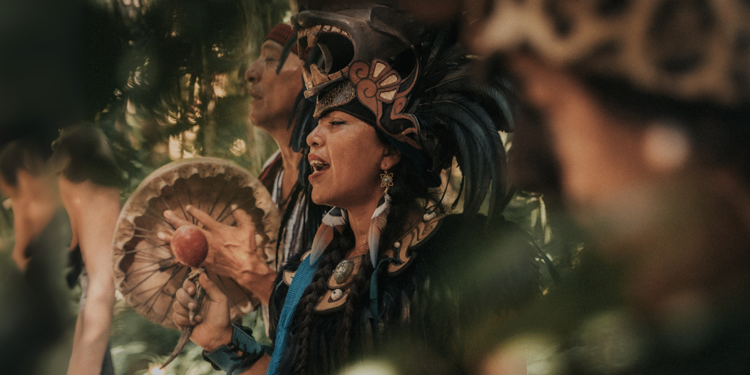 People in traditional attire performing a ceremonial ritual with drums in a lush jungle setting at Lunita Jungle Retreat.