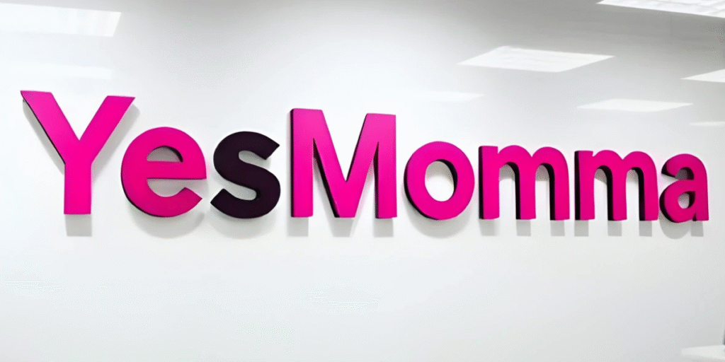 "The 'YesMomma' logo displayed in bold pink and purple letters on a white wall, showcasing a modern and vibrant design."