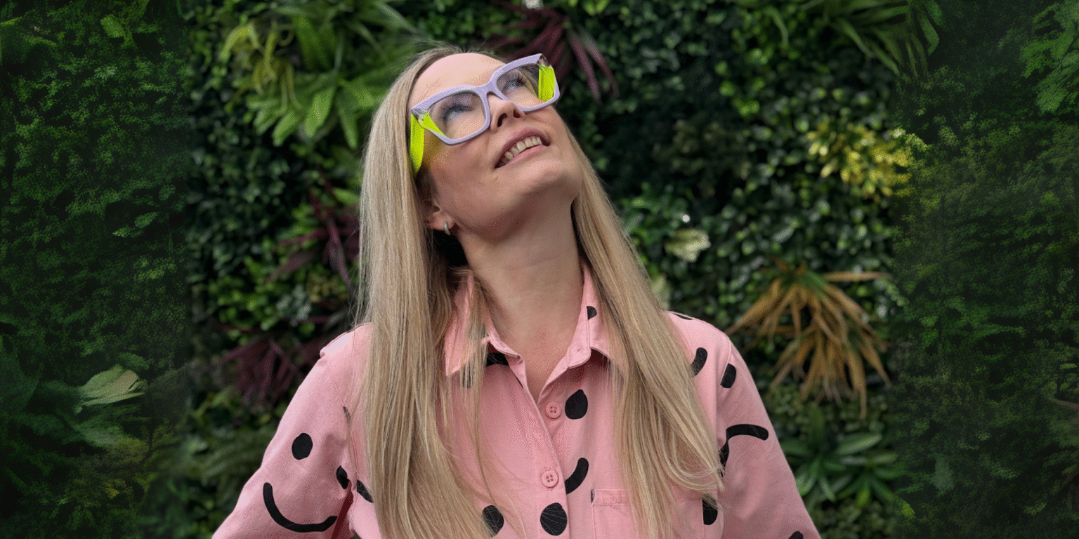 Emmaline McAndrew smiling in pink shirt, representing The Slow Businesswoman, a business platform for women with chronic illness.