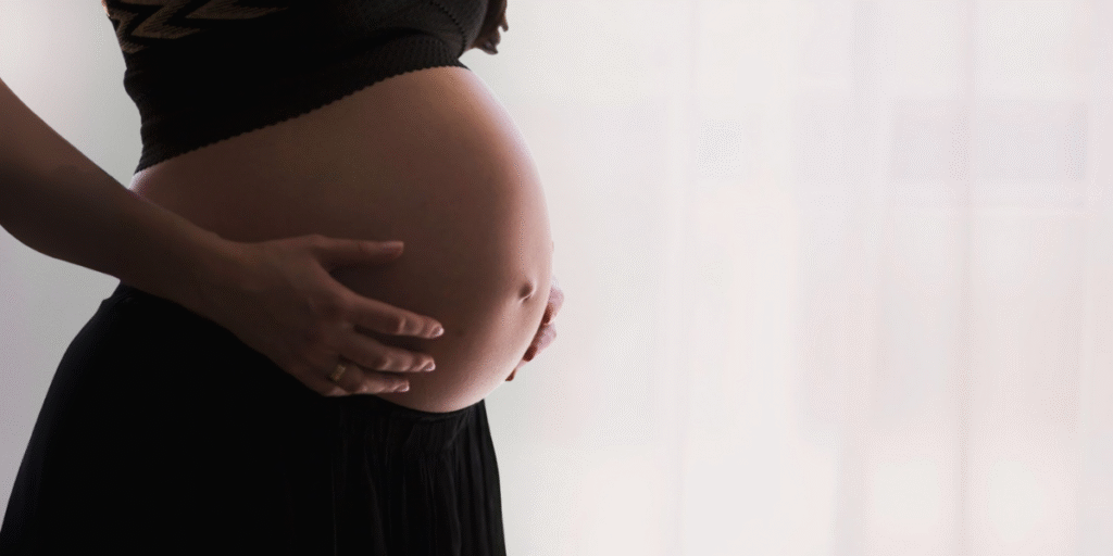 A pregnant woman gently holds her belly, symbolizing the challenges and legal protections surrounding pregnancy discrimination in California workplaces.