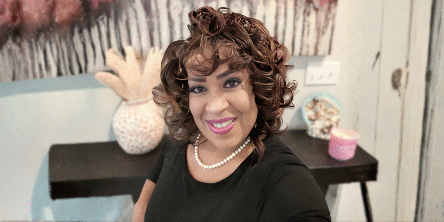 "Debra Savage smiling in a black top with a pearl necklace, representing her comedic ministry and faith-based mission."