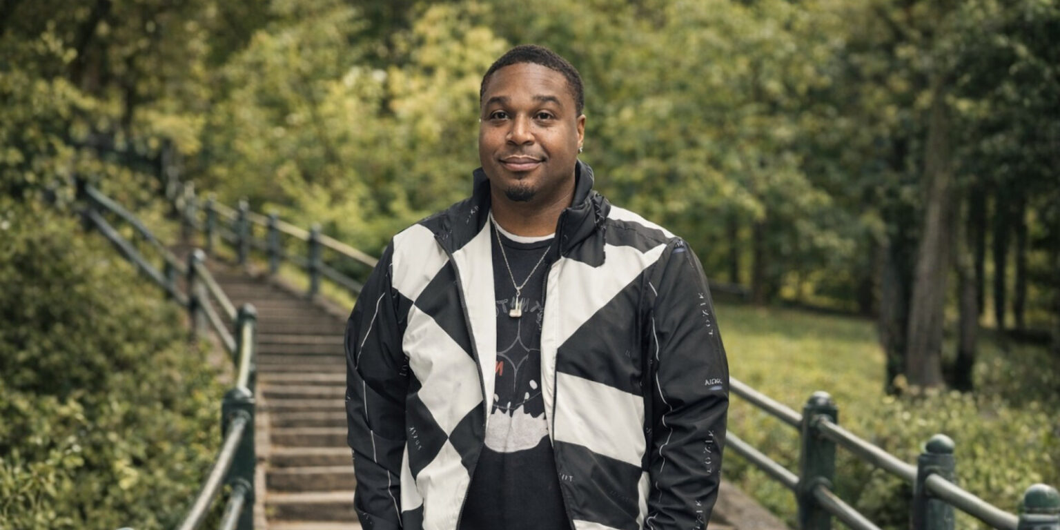 A confident man in streetwear jacket stands in front of outdoor stairs, embodying Toxik Nature's bold, expressive style.