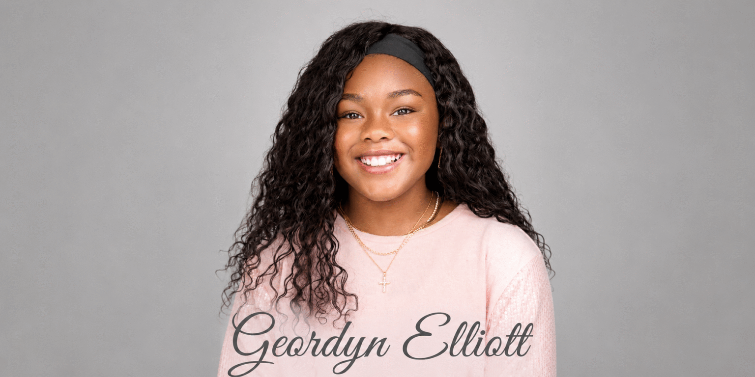 Geordyn Elliott Inspires Through Faith, Music, Writing, Leadership, And Academic Excellence Smiling young author Geordyn Elliott wearing a pink shirt and cross necklace against a gray background.