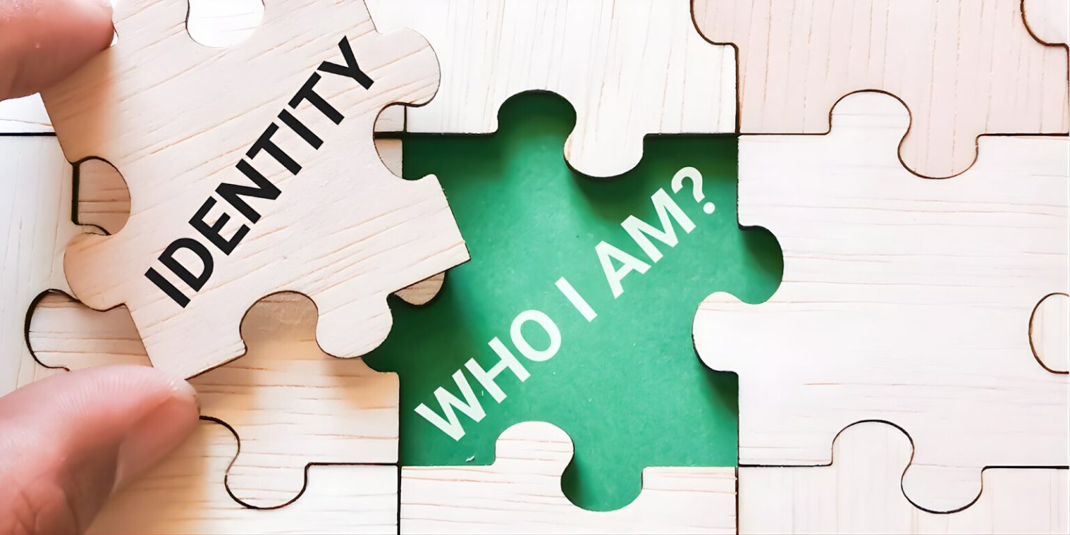A hand places a puzzle piece labeled "IDENTITY" into a missing space with the words "WHO I AM?" in green.