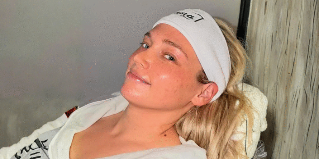 Woman wearing headband reclines during facial treatment, glowing skin in serene spa setting.