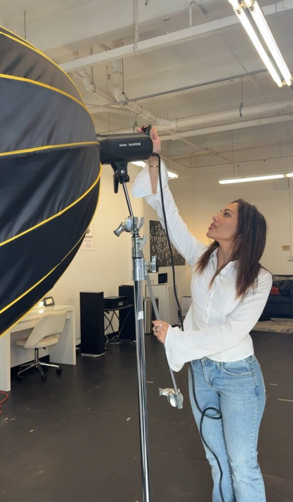 Hailey Howell adjusts studio lighting during a fashion shoot, showcasing Hails denim brand’s creative vision, individuality, culture, and storytelling aesthetic.